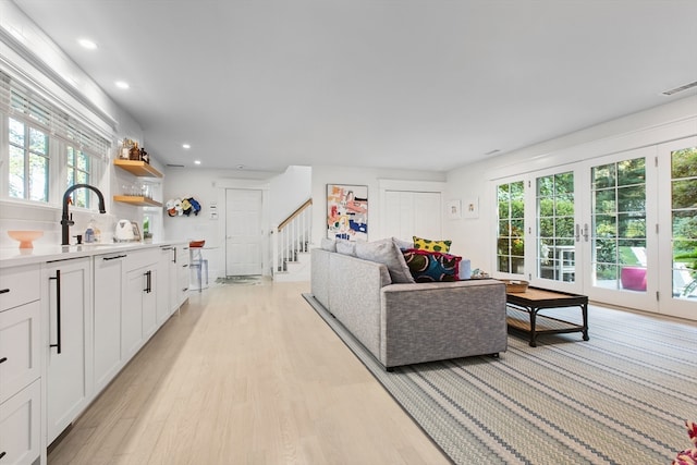 living room featuring sink, light hardwood / wood-style floors, and a wealth of natural light