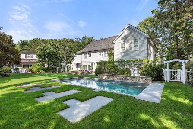 rear view of property featuring a lawn and a fenced in pool