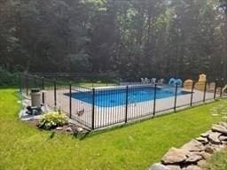 community pool featuring a patio area, a yard, and fence