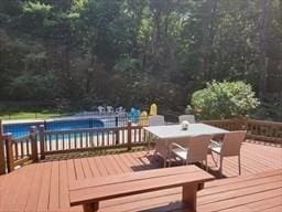 wooden terrace featuring outdoor dining space and an outdoor pool