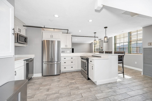 kitchen with white cabinets, hanging light fixtures, kitchen peninsula, appliances with stainless steel finishes, and a kitchen breakfast bar