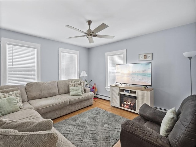 living room with baseboard heating, ceiling fan, and light hardwood / wood-style floors