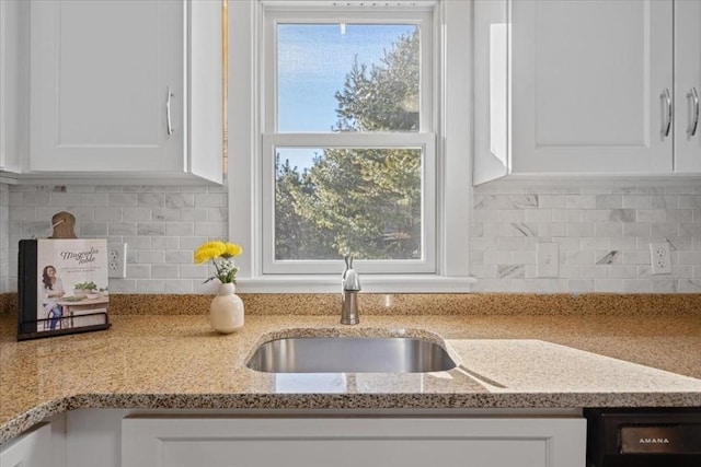 kitchen featuring sink, dishwasher, backsplash, light stone countertops, and white cabinets