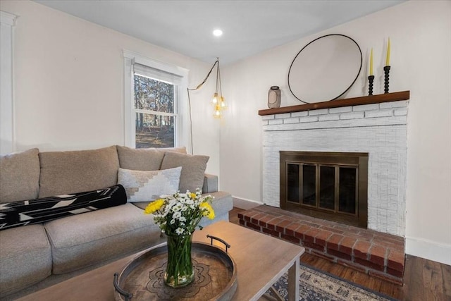 living room with wood-type flooring and a brick fireplace