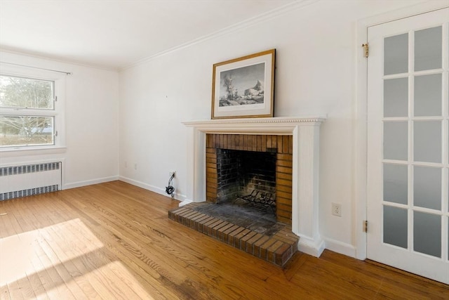 unfurnished living room with hardwood / wood-style floors, radiator heating unit, ornamental molding, and a fireplace