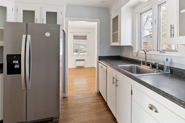 kitchen with wood-type flooring, stainless steel fridge, sink, white cabinets, and radiator