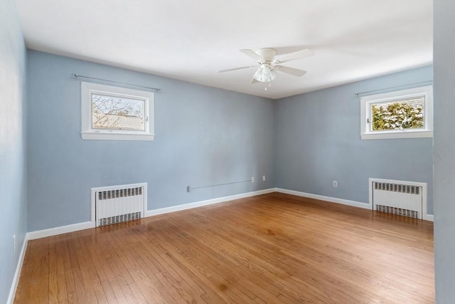 spare room with hardwood / wood-style flooring, radiator heating unit, and ceiling fan