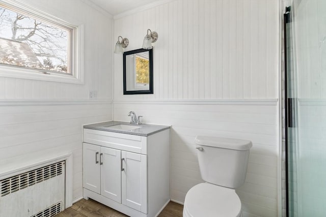 bathroom with hardwood / wood-style floors, toilet, radiator, and vanity