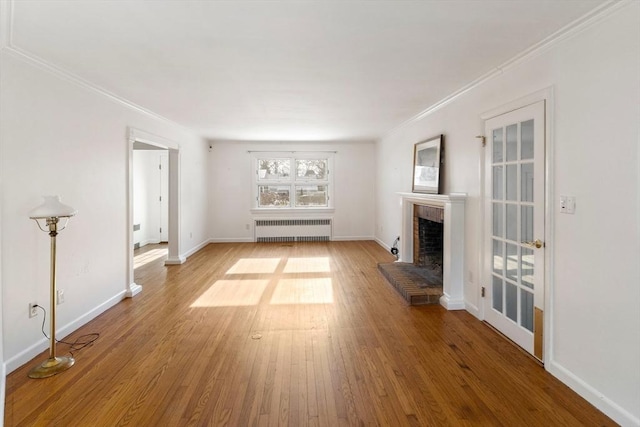 unfurnished living room featuring a brick fireplace, wood-type flooring, radiator heating unit, and crown molding