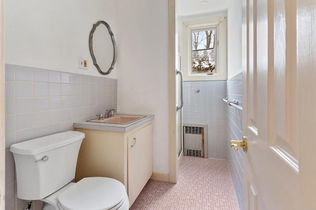 bathroom featuring toilet, tile patterned flooring, vanity, and tile walls