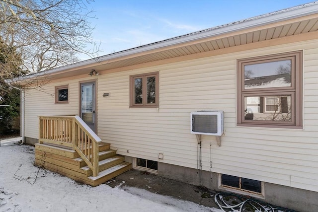 snow covered property entrance with a wall mounted AC