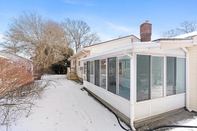 view of snowy exterior with a sunroom