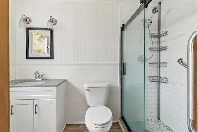 bathroom featuring hardwood / wood-style flooring, a shower with door, toilet, and vanity