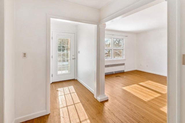 entrance foyer featuring a wealth of natural light, wood-type flooring, radiator, and ornate columns