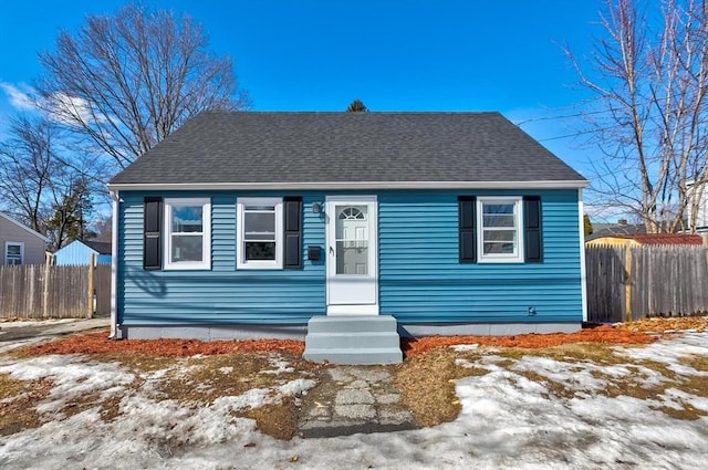 bungalow-style house featuring fence and roof with shingles