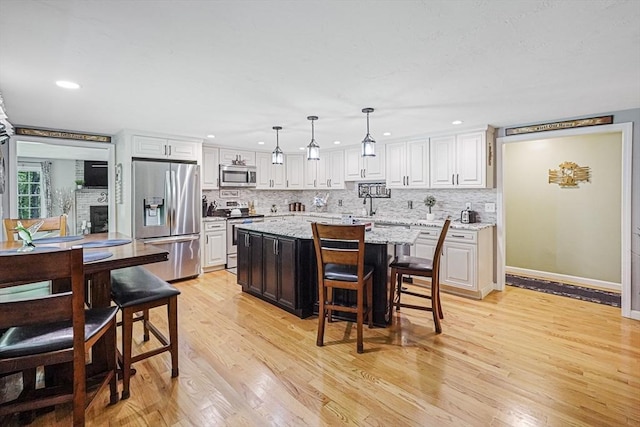 14 Daniels Rd, Charlton, MA 01507 - kitchen with stainless steel appliances, backsplash, light wood-type flooring, a kitchen island, and white cabinetry