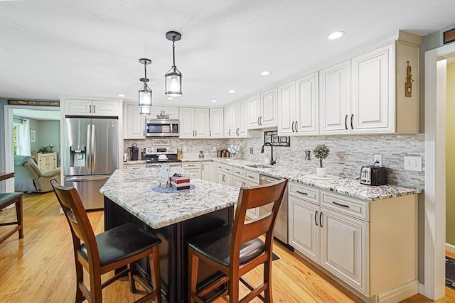 14 Daniels Rd, Charlton, MA 01507 - kitchen featuring appliances with stainless steel finishes, a sink, a breakfast bar, light wood-type flooring, and tasteful backsplash