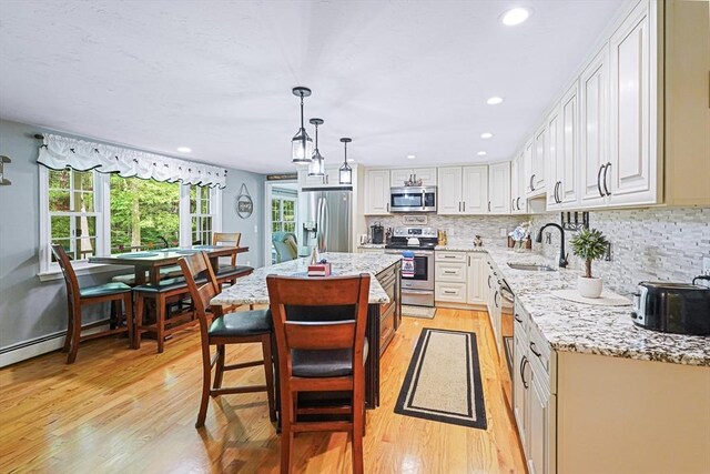 14 Daniels Rd, Charlton, MA 01507 - kitchen with appliances with stainless steel finishes, a sink, light wood finished floors, decorative backsplash, and light stone countertops