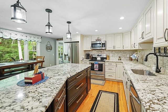 14 Daniels Rd, Charlton, MA 01507 - kitchen with stainless steel appliances, a sink, light wood-style flooring, decorative backsplash, and light stone counters