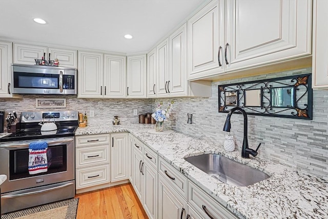 14 Daniels Rd, Charlton, MA 01507 - kitchen featuring appliances with stainless steel finishes, a sink, white cabinetry, decorative backsplash, and light wood-style floors