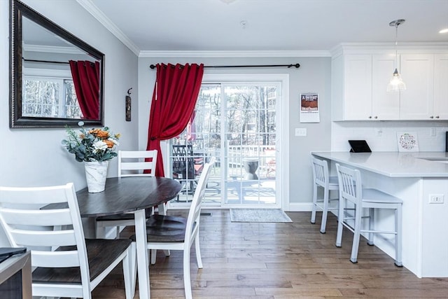 dining area featuring light wood-style flooring, baseboards, and ornamental molding