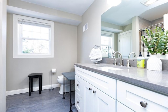 bathroom featuring visible vents, baseboards, toilet, and vanity