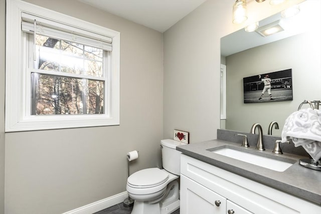 half bathroom with vanity, toilet, and baseboards