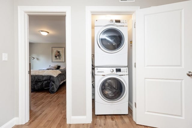 washroom with laundry area, light wood-style flooring, stacked washer and clothes dryer, and visible vents