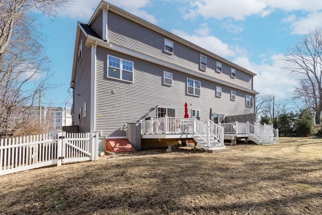 rear view of property with a deck, a gate, fence, and a yard