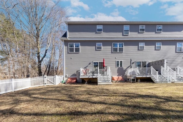 back of property with a fenced backyard, a lawn, a deck, and a gate