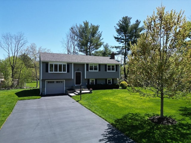 27 Ann St, Raynham, MA 02767 - raised ranch featuring a garage, a front yard, driveway, and a chimney