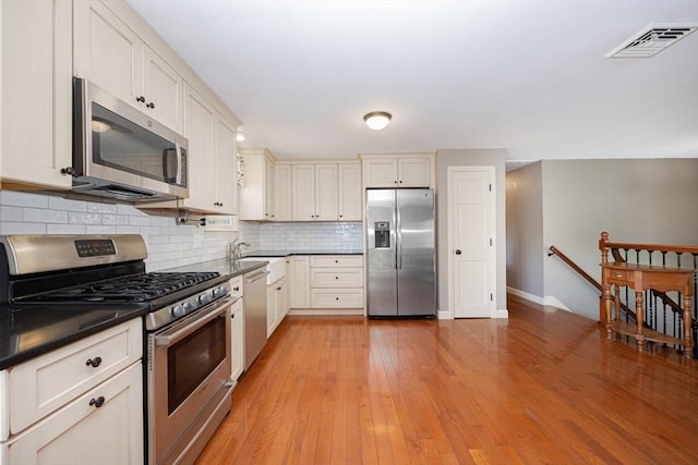 27 Ann St, Raynham, MA 02767 - kitchen featuring stainless steel appliances, dark countertops, tasteful backsplash, and light wood-style flooring