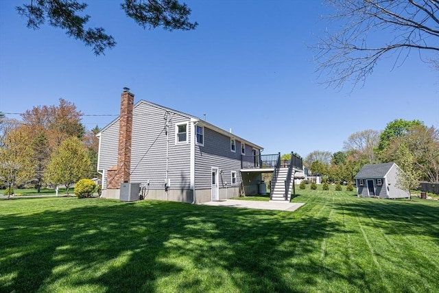 27 Ann St, Raynham, MA 02767 - back of property featuring stairs, a shed, a chimney, a yard, and a wooden deck