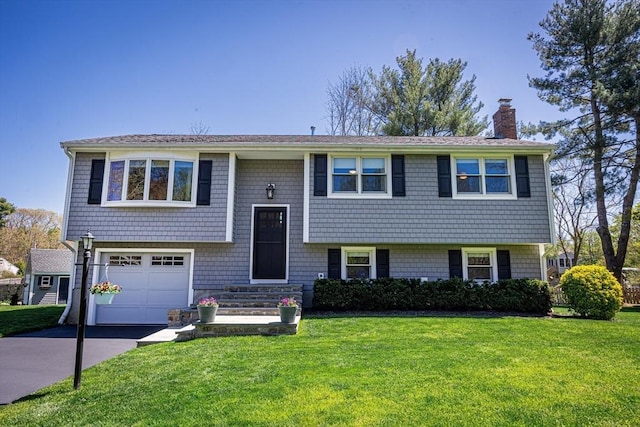 27 Ann St, Raynham, MA 02767 - bi-level home featuring a chimney, an attached garage, asphalt driveway, and a front yard