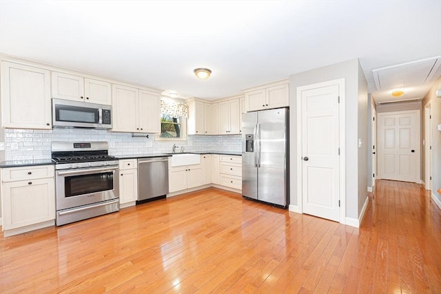 27 Ann St, Raynham, MA 02767 - kitchen with appliances with stainless steel finishes, decorative backsplash, dark countertops, and light wood-style floors
