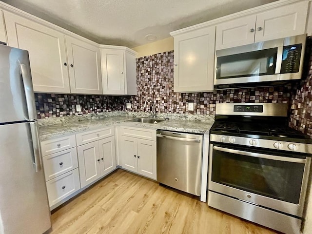 67 Oakcrest Rd, Boston, MA 02136 - kitchen featuring appliances with stainless steel finishes, white cabinets, light wood finished floors, decorative backsplash, and light stone countertops