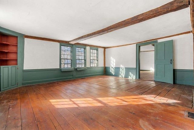 unfurnished room with beamed ceiling and hardwood / wood-style flooring