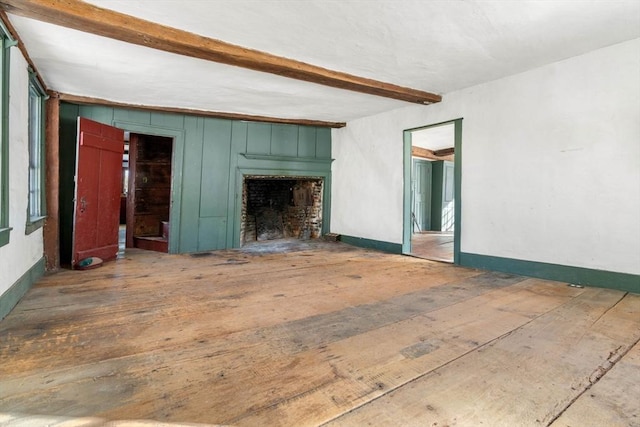 unfurnished living room with wood-type flooring, baseboards, and beam ceiling