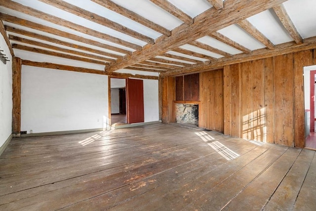 unfurnished living room featuring dark wood-style floors, wood walls, and beam ceiling