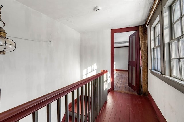 corridor featuring dark wood finished floors and an upstairs landing