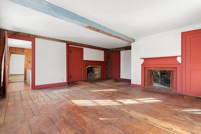 unfurnished living room featuring a fireplace, baseboards, hardwood / wood-style floors, and beamed ceiling