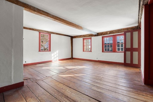 unfurnished room featuring beam ceiling, baseboards, and hardwood / wood-style floors