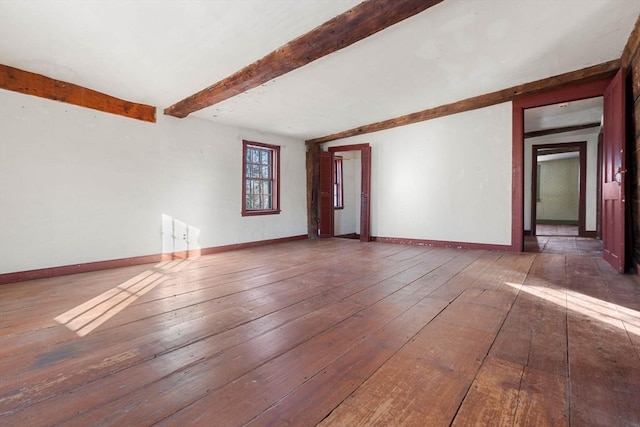 unfurnished room featuring beam ceiling, baseboards, and dark wood-type flooring