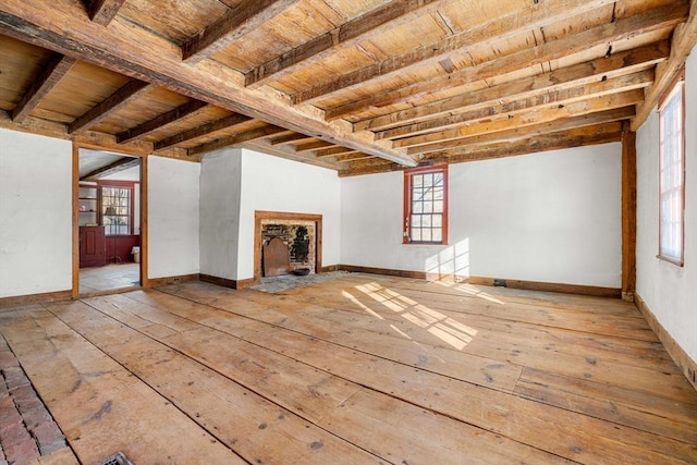 unfurnished living room featuring wooden ceiling, a fireplace, beam ceiling, and baseboards