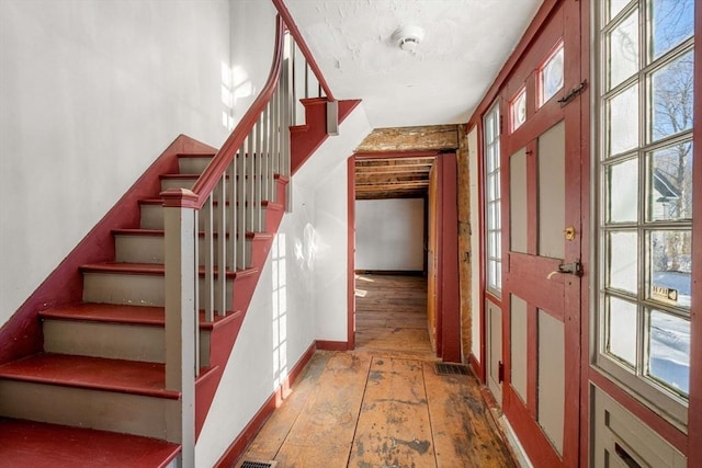 stairs with a healthy amount of sunlight, baseboards, and hardwood / wood-style floors