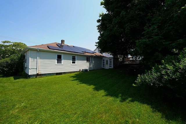 313 Walter St, Fall River, MA 02724 - rear view of property featuring solar panels, a lawn, and a chimney