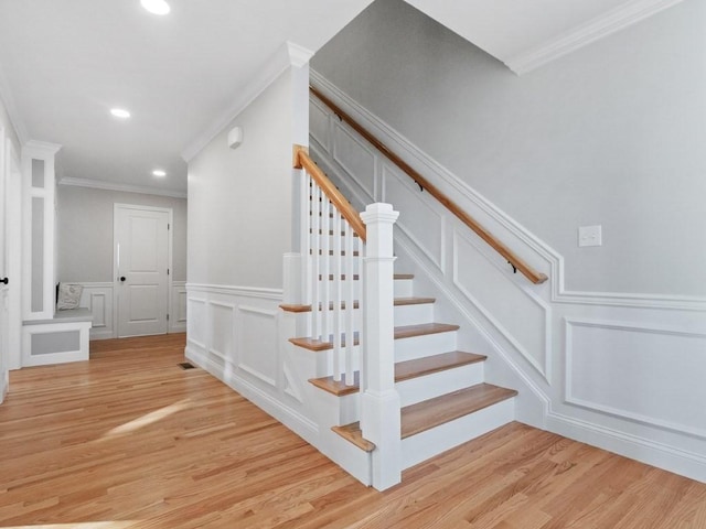 stairs with hardwood / wood-style flooring and ornamental molding