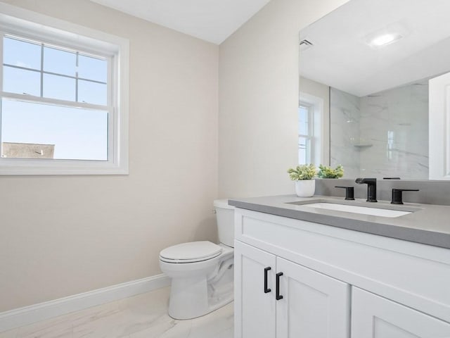 bathroom with toilet, vanity, and a tile shower