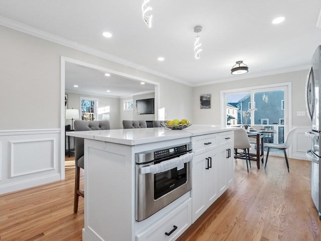 kitchen featuring white cabinetry, a center island, ornamental molding, and a breakfast bar area