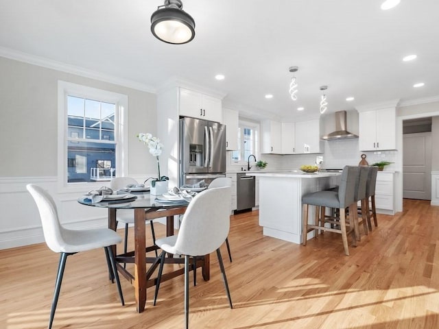 kitchen featuring white cabinetry, wall chimney range hood, appliances with stainless steel finishes, and a kitchen island